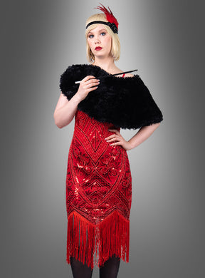 Eine Person, die das „Luxuriöse Kleid mit Pailletten Cleo“ trägt – ein rotes Flapper-Kleid mit Fransen, das an ein glamouröses Cocktailkleid erinnert –, kombiniert mit einer schwarzen Pelzstola und einem schwarzen Stirnband, das mit einer roten Feder verziert ist, hält eine Zigarettenspitze vor einem grauen Hintergrund mit Farbverlauf.