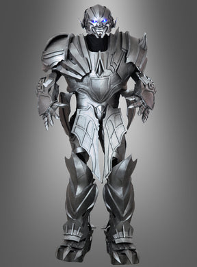 Ein metallischer humanoider Roboter mit leuchtend blauen Augen steht aufrecht da; er verfügt über kantige Panzerplatten und ein futuristisches Design, das an das „Megatronix 270 cm Roboformer Event“-Kostüm erinnert, vor einem grauen Hintergrund mit Farbverlauf.