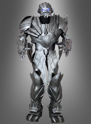 Ein metallischer humanoider Roboter mit leuchtend blauen Augen steht aufrecht da; er verfügt über kantige Panzerplatten und ein futuristisches Design, das an das „Megatronix 270 cm Roboformer Event“-Kostüm erinnert, vor einem grauen Hintergrund mit Farbverlauf.
