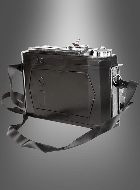 Eine Vintage-Fotokamera aus Blech mit Schulterriemen wird vor einem grauen Hintergrund mit Farbverlauf präsentiert und eignet sich somit perfekt als Vintage-Dekoration oder als Kostümaccessoire im Stil der 20er Jahre.