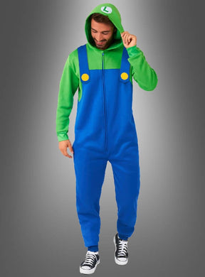 Eine Person, die einen grünen Kapuzenpulli und den „Luigi-Overall für Erwachsene“ trägt – ein blaues Kostüm mit gelben Knöpfen, inspiriert von der legendären Super-Mario-Spielfigur –, steht vor einem grauen Hintergrund mit Farbverlauf, wodurch es sich perfekt für Fasching-Feiern eignet.