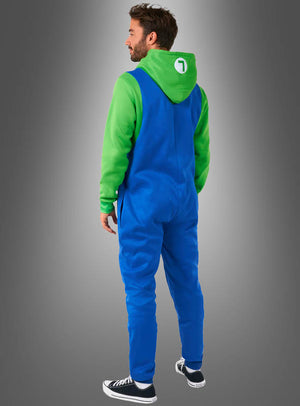 Ein Mann steht vor einem Hintergrund mit Farbverlauf und trägt den „Luigi-Overall für Erwachsene“, kombiniert mit einem grünen Hoodie, auf dessen Kapuze ein weißer Kreis und die Zahl 1 zu sehen sind – eine ideale Wahl für den Fasching oder als Teil eines Super-Mario-Kostüms –, dazu schwarze Sneaker; er steht mit dem Rücken zur Kamera.