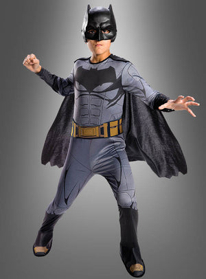 Eine Person, die ein komplettes Batman-Filmkostüm für Kinder aus „Justice League“ trägt – inspiriert von dem legendären DC-Comics-Lizenzprodukt –, steht in einer dynamischen Pose vor einem grauen Hintergrund mit Farbverlauf.