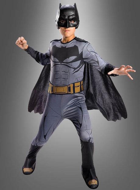 Eine Person, die ein komplettes Batman-Filmkostüm für Kinder aus „Justice League“ trägt – inspiriert von dem legendären DC-Comics-Lizenzprodukt –, steht in einer dynamischen Pose vor einem grauen Hintergrund mit Farbverlauf.