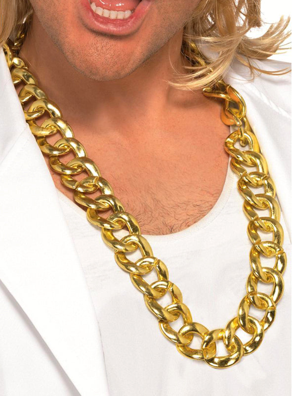 Eine Person, die eine große, klobige Halskette mit der Aufschrift „Halskette gold Goldkette Pimp“ trägt, dazu ein weißes Hemd und eine weiße Jacke. Zu sehen sind nur der untere Teil des Gesichts und der obere Brustbereich.