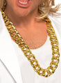 Eine Person, die eine große, klobige Halskette mit der Aufschrift „Halskette gold Goldkette Pimp“ trägt, dazu ein weißes Hemd und eine weiße Jacke. Zu sehen sind nur der untere Teil des Gesichts und der obere Brustbereich.