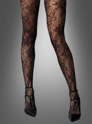 Eine Person, die die „Stilvolle Strumpfhose mit Blumenmuster“ und schwarze Schuhe mit hohen Absätzen trägt und vor einem grauen Hintergrund mit Farbverlauf steht.