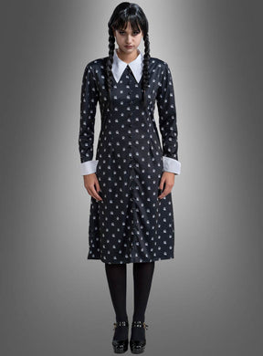 Eine Frau mit geflochtenen Zöpfen präsentiert das „Wednesday Damen Kleid schwarz-weiß“ – ein schwarzes Kleid mit weißem Kragen und weißen Manschetten, kombiniert mit schwarzen Strumpfhosen und Schuhen –, vor einem grauen Hintergrund mit Farbverlauf – ideal für alle, die ein Wednesday-Kostüm oder ein Addams-Family-Kostüm im klassischen Stil suchen.