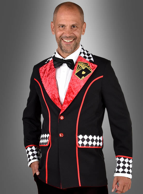 Ein Mann, der die „Deluxe Poker Face Jackett“ trägt – ein schwarzes Sakko mit roten Paspeln, karierten Akzenten und einem Aufnäher in Form einer Spielkarte –, kombiniert mit einem weißen Hemd und einer schwarzen Fliege, steht lächelnd vor einem grauen Hintergrund.