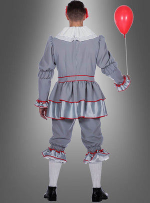 Eine Person, die das Halloween-Clown-Kostüm trägt – aus grauem Stoff mit Rüschen und roten Borten –, hält einen roten Luftballon in der Hand und steht mit dem Rücken zur Kamera.