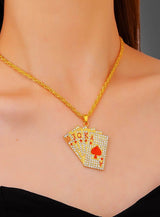 Eine Person in einem schwarzen Oberteil trägt die auffällige „Casino Spielkarten“-Halskette in Silber oder Gold, deren Anhänger in Form von mit Edelsteinen besetzten Spielkarten einen Royal Flush in Herz zeigt – damit ist sie der perfekte Las-Vegas-Schmuck und ein ideales Kostüm-Accessoire für jeden Kartenliebhaber.