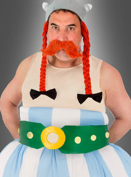 Ein Mann, gekleidet wie ein Wikinger aus einem Comic – komplett mit gehörntem Helm, orangefarbenen Zöpfen, großem orangefarbenem Schnurrbart, gestreiften Hosen und einem breiten grünen Gürtel – steht vor einem grauen Hintergrund und präsentiert das Deluxe-Obelix-Kostüm XXL für Erwachsene aus „Asterix“: das ideale Gallier-Kostüm und ein auffälliges Herren-Faschingskostüm.