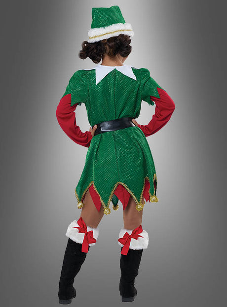 Eine Person, die das „Süße Weihnachtselfe“-Kinderkostüm trägt – bestehend aus einem grün-roten Elfenoutfit mit Mütze, schwarzen Stiefeln und roten Schleifen –, steht mit dem Rücken zur Kamera vor einem grau verlaufenden Hintergrund und verkörpert damit perfekt die festliche Stimmung für jede Weihnachtsfeier.