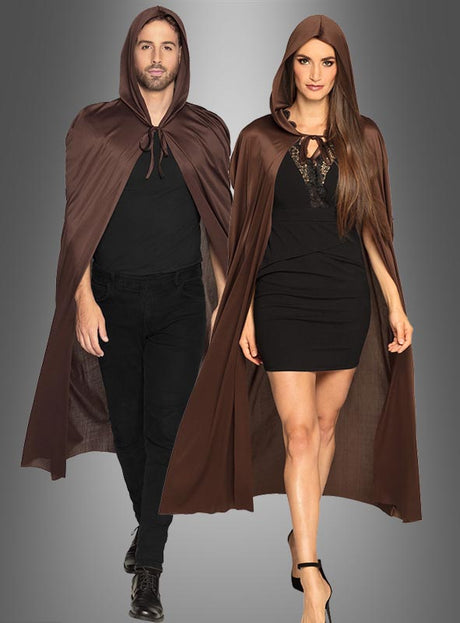 Ein Mann und eine Frau stehen nebeneinander und tragen passende braune Umhänge „Umhang mit Kapuze in verschiedenen Farben 140 cm“ über schwarzen Outfits vor einem grauen Hintergrund – ein auffälliger Look, der sich perfekt für jedes Halloween-Kostüm eignet.