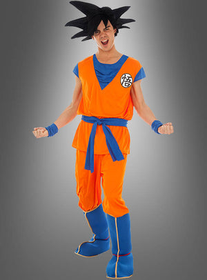 Eine Person in einem Son-Goku-Kostüm aus „Dragon Ball Z“ in den Farben Orange und Blau mit stacheligen schwarzen Haaren, die mit geballten Fäusten und entschlossenem Gesichtsausdruck vor einem grauen Hintergrund mit Farbverlauf steht.