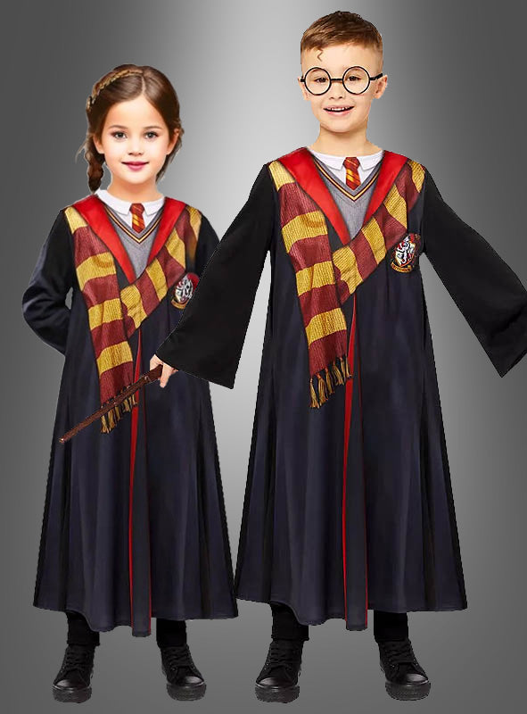 Zwei Kinder, gekleidet in die bedruckte Harry-Potter-Robe mit Zauberstab und Brille – bestehend aus schwarzen Hogwarts-Schuluniformmänteln, gestreiften Schals und Krawatten –, stehen vor einem grauen Hintergrund – das eine hält einen Zauberstab in der Hand, das andere trägt eine runde Brille.