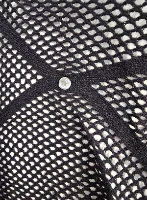 Nahaufnahme des schwarzen Stoffes „Stylische Strumpfhose mit Glitzersteinchen“, der von schwarzen Bändern durchzogen ist, die ein X bilden, in dessen Mitte sich ein kleiner runder Nietenstift befindet.