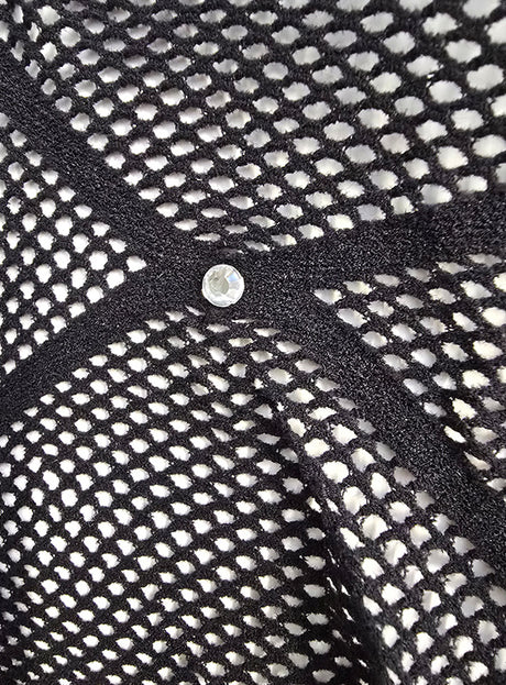 Nahaufnahme des schwarzen Stoffes „Stylische Strumpfhose mit Glitzersteinchen“, der von schwarzen Bändern durchzogen ist, die ein X bilden, in dessen Mitte sich ein kleiner runder Nietenstift befindet.