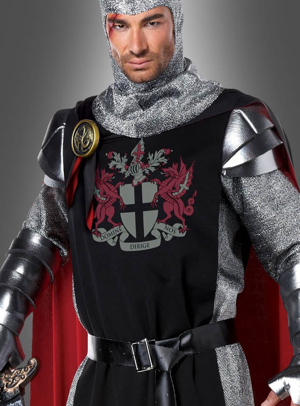 Ein Mann in einem mittelalterlichen Ritterkostüm, bestehend aus einer silbernen Ritterrüstung, einer Kettenhaube und einer schwarzen Tunika, die mit einem rot-weißen Wappen verziert ist, auf dem zwei rote Drachen und ein lateinisches Motto zu sehen sind – eine beeindruckende Aufmachung für jeden angehenden Helden.