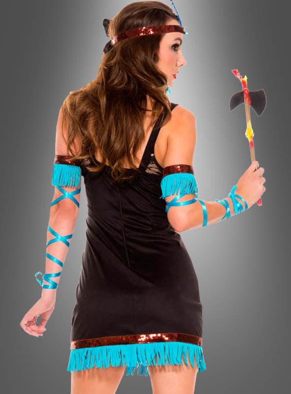 Eine Frau im „Indianer-Prinzessin“-Komplettkostüm – bestehend aus einem schwarzen Kleid mit blauen Fransen und passenden Armbändern, die einen Spielzeug-Tomahawk in der Hand hält und von hinten vor einem grauen Hintergrund zu sehen ist – eine auffällige Wahl für jede Wild-West-Mottoparty oder als markantes Indianerinnen-Kostüm.