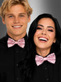 Zwei Personen in schwarzen Hemden und funkelnden „Rosa Pailletten Fliege“-Unisex-Fliegen lächeln vor einem grauen Hintergrund mit Farbverlauf und präsentieren ihr auffälliges Party-Accessoire. Diese farbenfrohen Fliegen eignen sich perfekt als Glitzerfliege für Damen und Herren und verleihen jedem festlichen Anlass einen Hauch von Spaß.