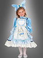 Ein kleines Mädchen steht lächelnd vor einem grauen Hintergrund und trägt das „Alice Deluxe“-Kinderkostüm – bestehend aus einem blau-weißen Rüschenkleid mit einer herzförmigen Schürze, einem Stirnband mit Hasenohren und weißen Strumpfhosen.