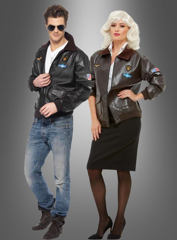 Ein Mann und eine Frau stehen nebeneinander vor einem grauen Hintergrund mit Farbverlauf; beide tragen die Unisex-Fliegerjacke „Original Top Gun“, die mit charakteristischen Aufnähern verziert ist, sowie Sonnenbrillen; er kombiniert seine Jacke mit Jeans, während sie ihre zu einem schwarzen Rock und Pumps trägt.