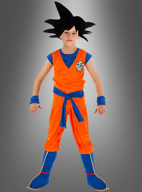 Ein Kind im Son-Goku-Kostüm für Kinder aus „Dragon Ball Z“ – bestehend aus einem orange-blauen Kampfsportanzug und einer schwarzen Perücke mit Stacheln – steht vor einem grauen Hintergrund mit Farbverlauf. Ideal für junge „Dragon Ball Z“-Fans und perfekt für ein Goku-Cosplay.