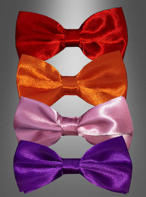 Vier farbige „Deluxe-Satin-Fliegen 13 x 6 cm“ in Rot, Orange, Pink und Lila sind elegant übereinander vor einem sanften grauen Farbverlauf angeordnet – die perfekten Satin-Fliegen für Herren, um stilvolle Outfits zu vervollständigen und als elegante Accessoires zu glänzen.
