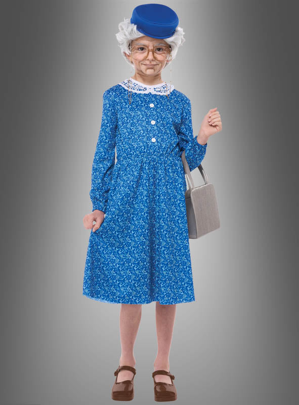 Ein Kind steht vor einem grauen Hintergrund und trägt das Oma-Kostüm für Mädchen, bestehend aus einem blau gemusterten Kleid, einer runden Brille, einer Oma-Perücke (graue Perücke), einem blauen Hut, braunen Schuhen und einer grauen Handtasche.