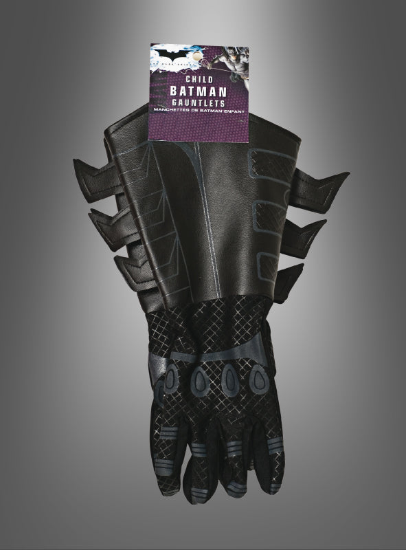 Ein Paar Kinderhandschuhe für das Batman-Kostüm „The Dark Knight“ in Schwarz, in Kindergröße mit seitlichen Flossen, inspiriert von „The Dark Knight“, verpackt und vor einem grauen Hintergrund mit Farbverlauf präsentiert.