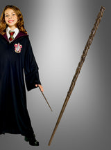 Eine Person in einer schwarzen Robe mit Wappen hält einen kleinen Zauberstab in der Hand, der an die legendären Harry-Potter-Zauberstäbe erinnert; daneben ist der „Hermine Deluxe Zauberstab Harry Potter“ vor einem grauen Hintergrund mit Farbverlauf deutlich zu sehen.