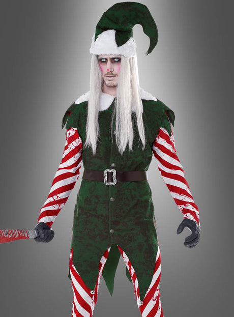 Vor einem grauen Hintergrund mit Farbverlauf steht eine Person, die das „Horror-Weihnachtself-Kostüm mit Perücke“ trägt – ein dunkles Elfenoutfit mit langen weißen Haaren, rot-weiß gestreiften Ärmeln, einer grünen Mütze und einem rot markierten Schläger in der Hand. Dieses Kostüm ist ideal, um Ihren Weihnachtsfeiern eine gruselige Note zu verleihen.