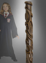 Ein Mädchen in einer schwarzen Robe mit einem Gryffindor-Abzeichen steht neben einer Nahaufnahme des „Hermine Deluxe“-Zauberstabs aus der Harry-Potter-Reihe, vor einem grauen Hintergrund mit Farbverlauf.