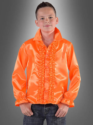 Ein junger Mensch trägt ein leuchtend orangefarbenes Rüschenhemd für Kinder in verschiedenen Farben, kombiniert mit Jeans, und steht vor einem grauen Hintergrund mit Farbverlauf – das ideale 70er-Jahre-Kostüm oder Disco-Party-Outfit für jede Feier im Retro-Stil.