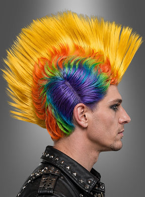 Eine Person im Profil mit einem hohen, stacheligen Irokesenschnitt in Regenbogenfarben, die eine schwarze Lederjacke mit Metallnieten trägt – perfekt für den Karneval oder als auffällige bunte Punk-Perücke im Irokesen-Stil – vor einem grauen Hintergrund mit Farbverlauf.