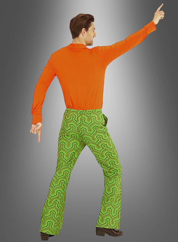 Eine Person in einem orangefarbenen Shirt und der „Retro Hose Herren grün“ posiert mit einem Arm nach oben und dem anderen nach unten gerichtet vor einem grauen Hintergrund mit Farbverlauf.