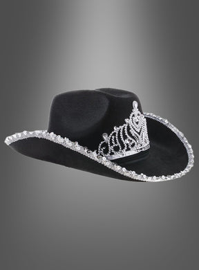 „Cowgirl Hut mit Krone“ – ein schwarzer Cowboyhut mit einem auffälligen silbernen Tiara-Motiv auf der Vorderseite und schimmernden silbernen Verzierungen entlang der Krempe, präsentiert vor einem eleganten grauen Hintergrund mit Farbverlauf. Dieser stilvolle Westernhut ist ideal, um jedem Outfit einen glamourösen Akzent zu verleihen.