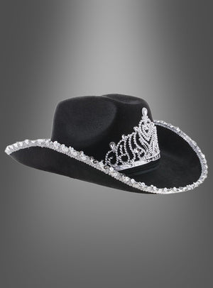 „Cowgirl Hut mit Krone“ – ein schwarzer Cowboyhut mit einem auffälligen silbernen Tiara-Motiv auf der Vorderseite und schimmernden silbernen Verzierungen entlang der Krempe, präsentiert vor einem eleganten grauen Hintergrund mit Farbverlauf. Dieser stilvolle Westernhut ist ideal, um jedem Outfit einen glamourösen Akzent zu verleihen.