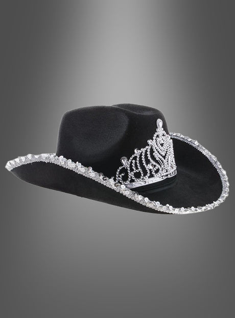 „Cowgirl Hut mit Krone“ – ein schwarzer Cowboyhut mit einem auffälligen silbernen Tiara-Motiv auf der Vorderseite und schimmernden silbernen Verzierungen entlang der Krempe, präsentiert vor einem eleganten grauen Hintergrund mit Farbverlauf. Dieser stilvolle Westernhut ist ideal, um jedem Outfit einen glamourösen Akzent zu verleihen.