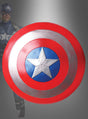 Eine Person in einem Captain-America-Kostüm hält das Captain-America-Schild (groß, 60 cm) in der Hand, das aus roten, weißen und blauen konzentrischen Kreisen mit einem silbernen Stern in der Mitte besteht – ein unverzichtbares Marvel-Superhelden-Schild für die Captain-America-Kostümzubehör-Sammlung jedes Fans.