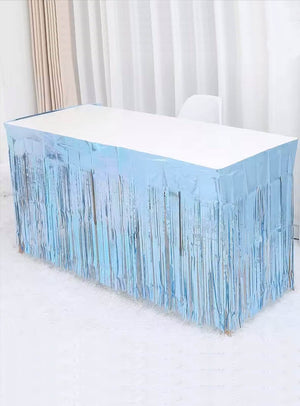 Ein rechteckiger Tisch, der mit einer weißen Tischdecke bedeckt und mit dem blauen Lametta-Tischrock (75 x 275 cm) als Tischumrandung verziert ist, bildet in einem hellen Raum mit weißen Vorhängen die perfekte Partydekoration.