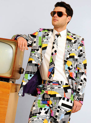 Ein Mann in einem farbenfrohen „Deluxe Testbild“-Anzug von OppoSuits und mit Sonnenbrille lehnt an einem Retro-Fernseher – die ideale Wahl für eine 70er-Jahre-Mottoparty oder als auffälliges Karnevalskostüm.