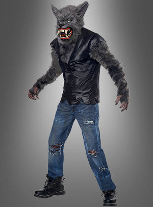 Ein Kind im Werwolf-Kinderkostüm – bestehend aus einer pelzigen Werwolf-Maske, einem zerrissenen schwarzen Hemd, pelzigen Handschuhen, zerrissenen blauen Jeans und schwarzen Stiefeln – steht vor einem schlichten grauen Hintergrund.
