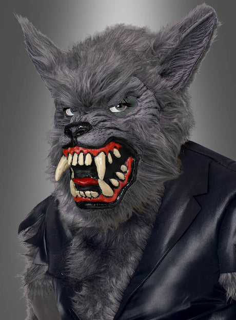 Ein Kind trägt das Werwolf-Kinderkostüm, bestehend aus einer detailreichen grauen Maske mit scharfen Reißzähnen und spitzen Ohren sowie einer schwarzen Jacke vor einem grauen Hintergrund mit Farbverlauf.