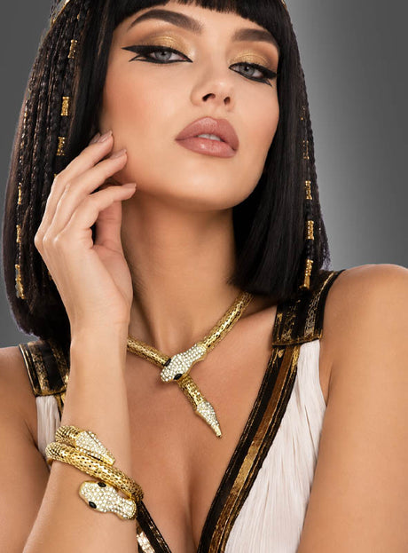 Eine Frau in einem von Kleopatra inspirierten Kostüm mit schwarzem Bob-Haarschnitt, auffälligem Eyeliner und markantem Goldschmuck aus dem „Schlangen-Schmuck-Set mit Strass“, der die Form von Schlangen hat und mit Strasssteinen verziert ist, posiert mit einer Hand nahe ihrem Gesicht vor einem grauen Hintergrund.