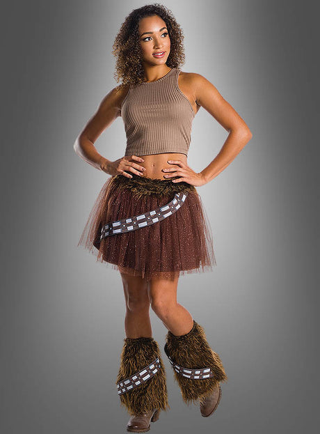 Vor einem grauen Hintergrund steht eine Frau, die einen Chewbacca-Wookiee-Tüllrock trägt, der von der legendären „Star Wars“-Figur inspiriert ist. Das Outfit besteht aus einem braunen Oberteil, dem charakteristischen Chewbacca-Wookiee-Tüllrock mit Bandelier-Details und passenden pelzigen Stulpen – die perfekte Kostümwahl für alle Fans, die den klassischen Look nachstellen möchten.