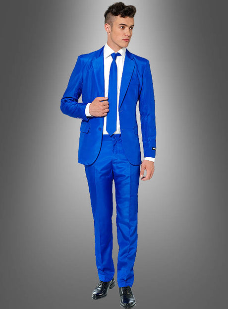 Ein Mann, der einen blauen „Anzug für Herren“ von Suitmeister, ein weißes Hemd und eine blaue Krawatte trägt, steht vor einem grauen Hintergrund mit Farbverlauf.