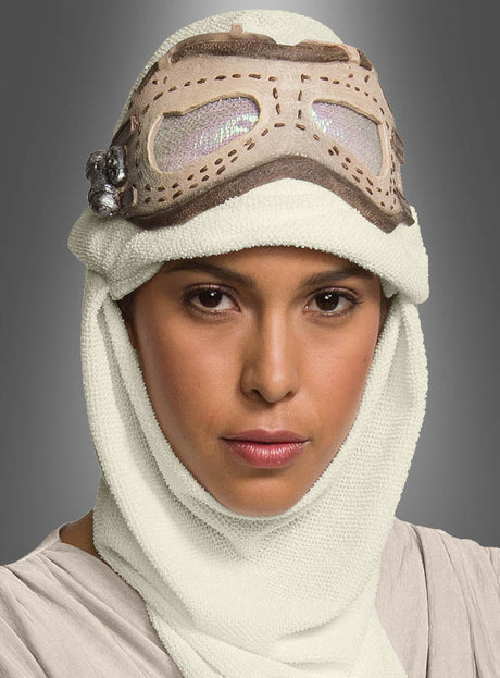Eine Person trägt die „Star Wars Rey Brille und Haube für Erwachsene“ mit einem cremefarbenen Kopftuch und einer Brille im Vintage-Stil auf der Stirn und posiert mit ausdruckslosem Gesicht vor einem grauen Hintergrund.