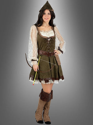 Eine Frau, die das Robin-Hood-Kostüm für Damen mit Spitzenärmeln, einem spitzen Hut und braunen Stiefeln trägt, hält einen kleinen Bogen und einen Pfeil in der Hand, während sie vor einem grauen Hintergrund steht.